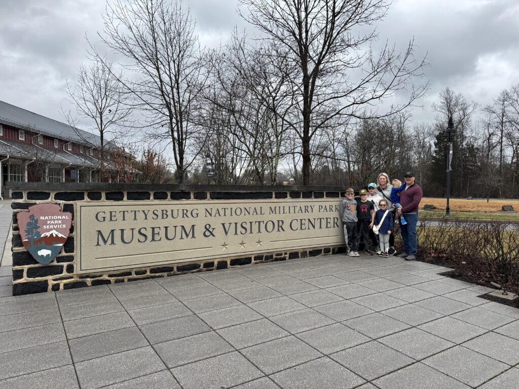 family in front of gettysburg national military park sign