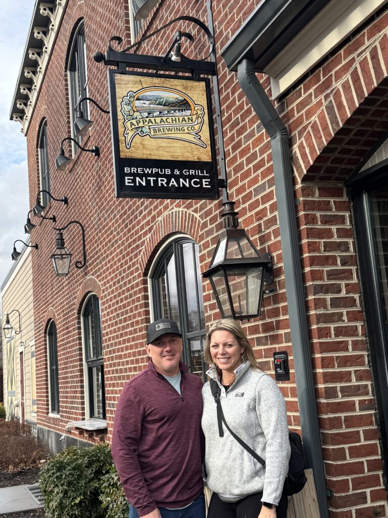 man and woman in front of appalachian brewing co sign