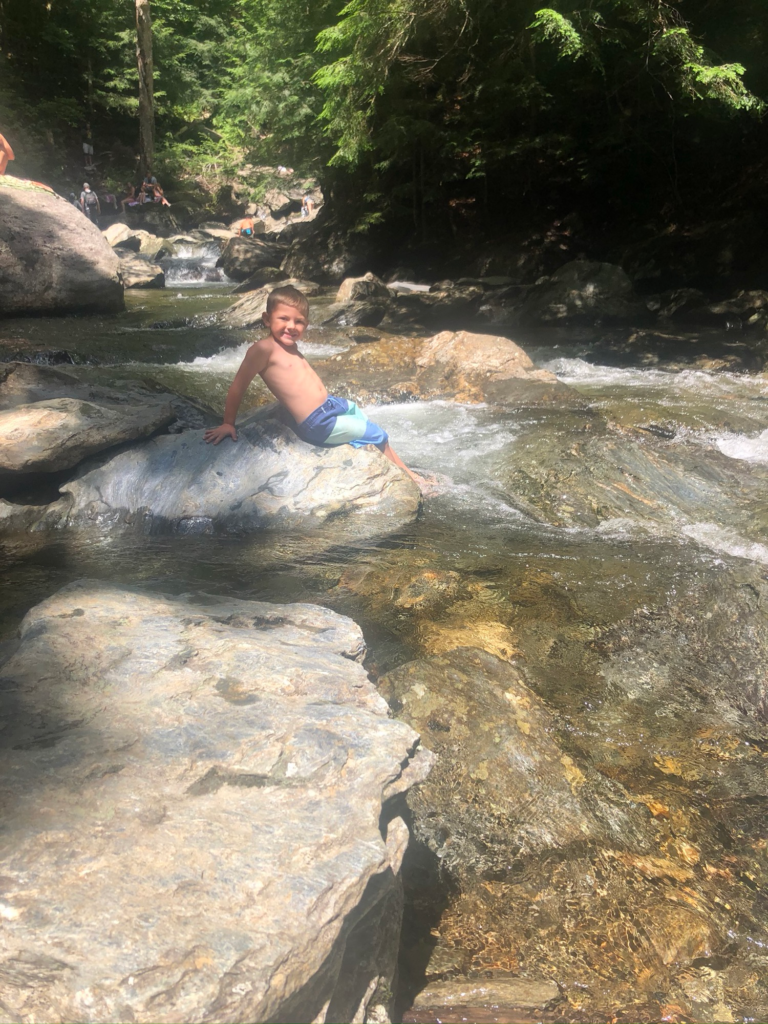 boy in bingham falls in stowe vermont during summer