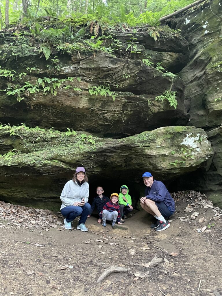 family under rocks in rock trail hocking hills with kids